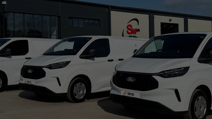 three white Ford Transit vehicles in front of SM UK headquarters