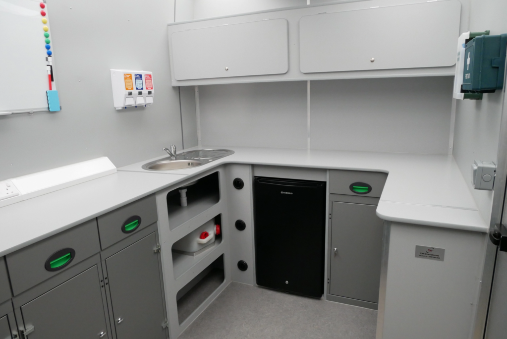 Interior of a van conversion by SM UK showing Kitchen area with sink, fridge and cupboards